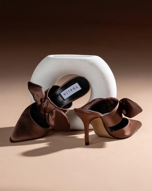 Brown high-heeled shoes with a bow design on a beige background - Thalia vegan sustainable dubai