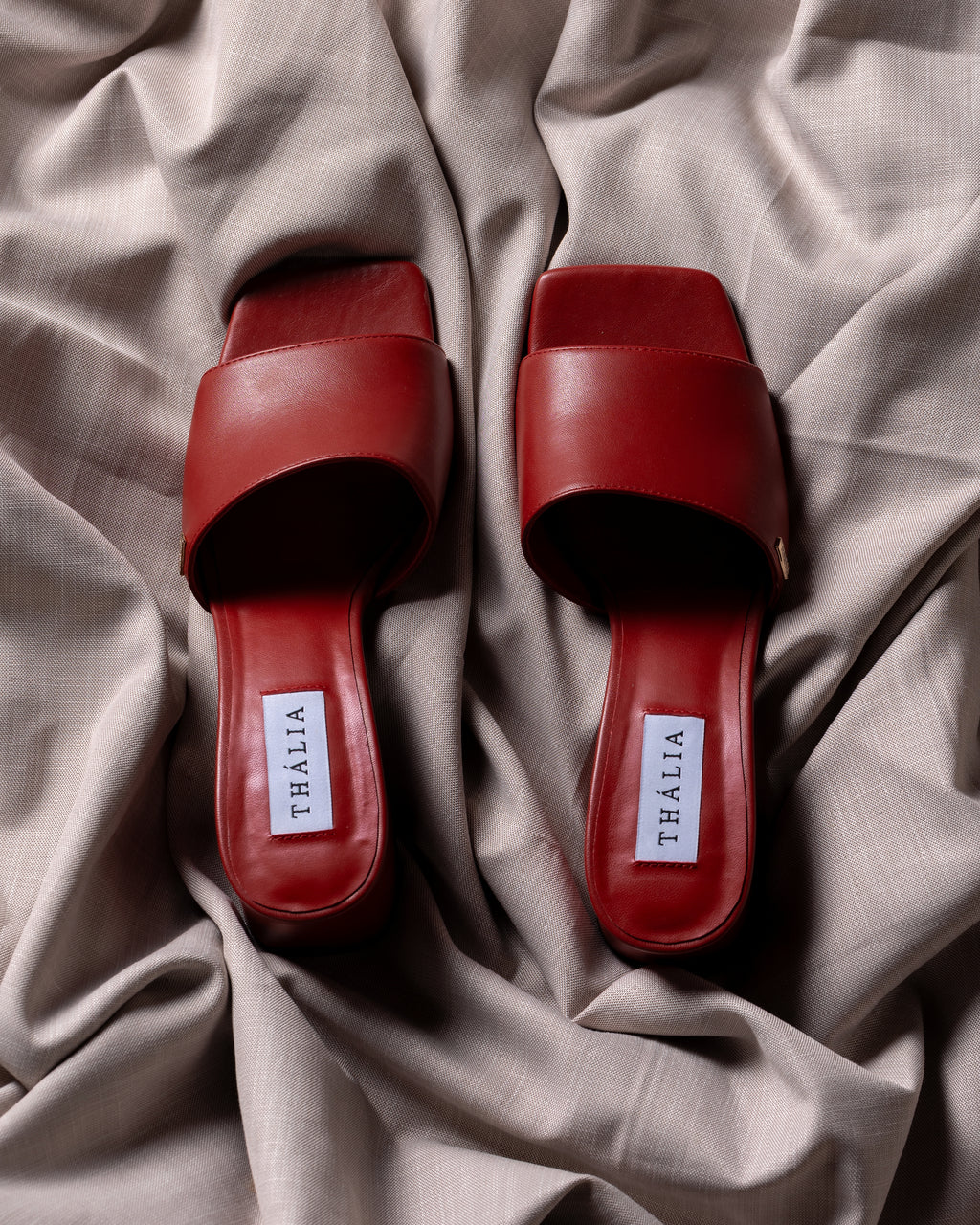 Red sandals with 'Thália' label on a beige fabric background - block heels 