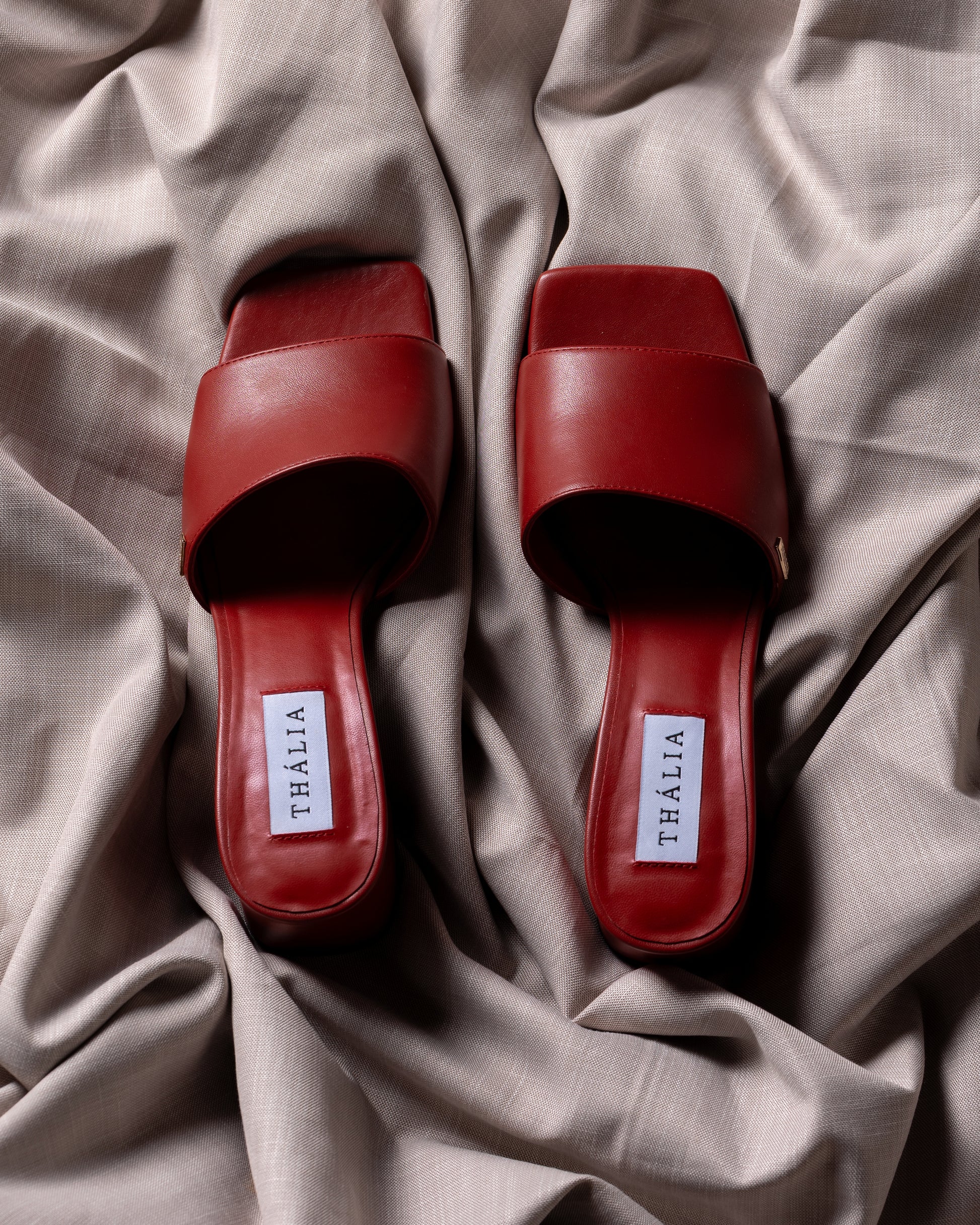 Red sandals with 'Thália' label on a beige fabric background - block heels 