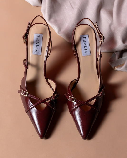 Pair of brown pointed-toe shoes with Thalia label on a beige background 